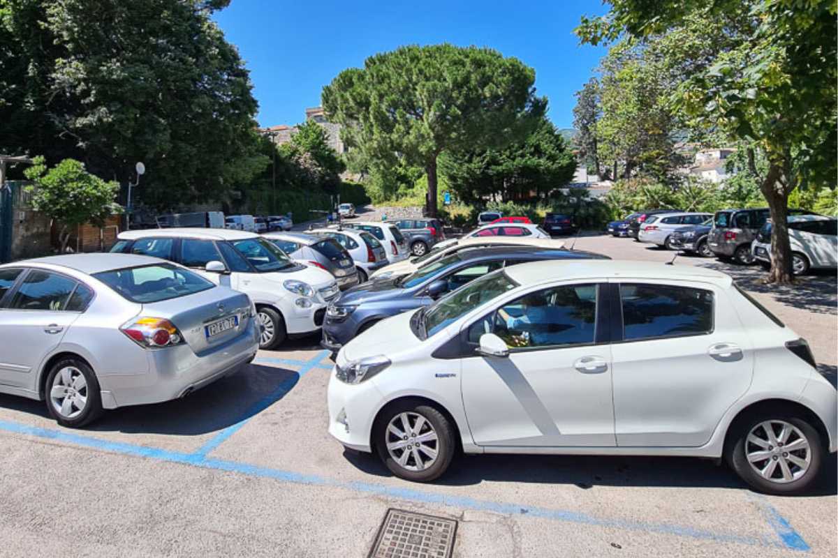 Parcheggio grande e ombreggiato vicino al centro di Porto Cesareo, gente che si avvia verso la spiaggia, estate